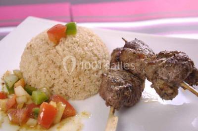 Un couple coupe un gâteau de mariage entouré de desserts décorés et de cierges magiques allumés.