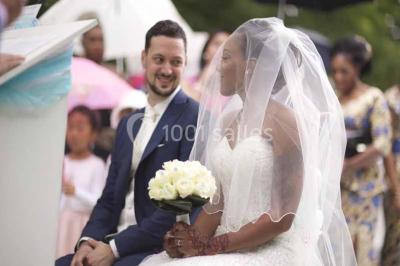 Un couple coupe un gâteau de mariage entouré de desserts décorés et de cierges magiques allumés.