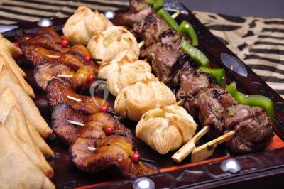 Plateau de verrines colorées garnies de fruits frais comme kiwi, fraise et mangue, tenu par une personne.