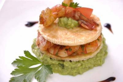 Plateau de verrines colorées garnies de fruits frais comme kiwi, fraise et mangue, tenu par une personne.