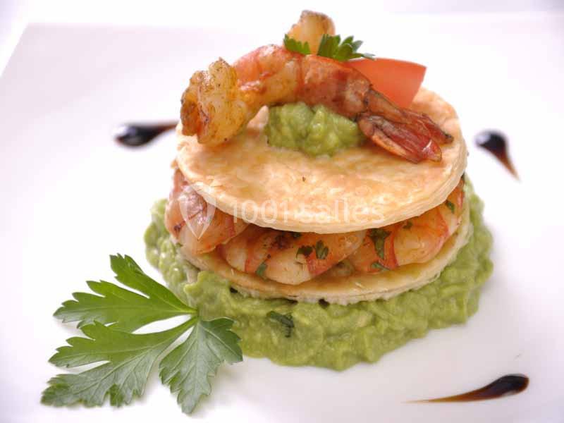 Millefeuille de crevettes sur lit de purée d'avocat, décoré de persil, tomate et sauce balsamique.