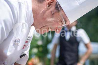 Boule croustillante sur lit de salade, garnie d'une framboise et décorée de sauce rouge sur assiette blanche.