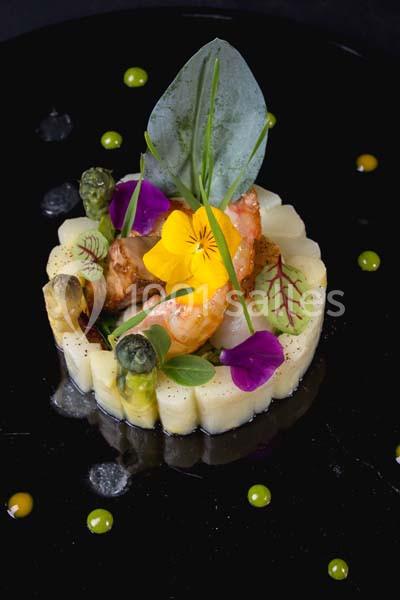 Assiette gastronomique avec purée dressée en cercle, asperges, crevettes, fleurs comestibles et sauce verte.