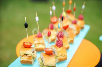 Plateau de bouchées apéritives variées avec charcuterie, légumes, verrines et décorations colorées.