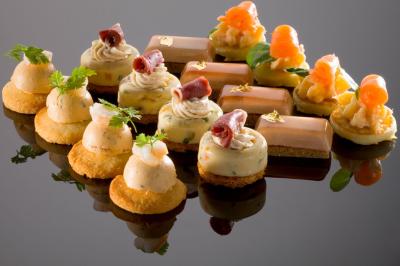 Assiette gastronomique avec trois noix de Saint-Jacques sur des légumes colorés, décorée de fines tranches et d'herbes.