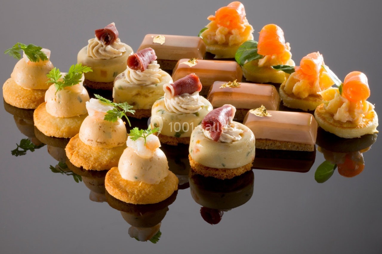 Assortiment de bouchées salées élégamment présentées sur une surface réfléchissante.