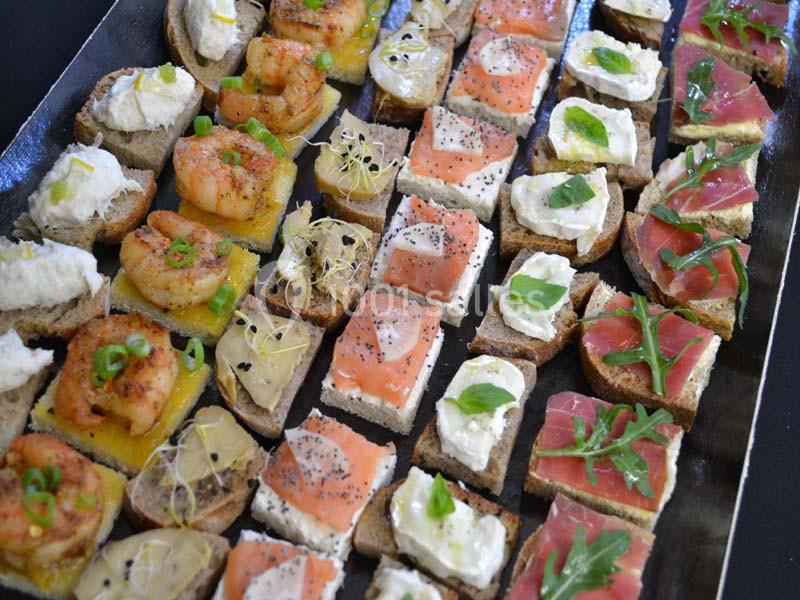 Plateau de canapés variés avec crevettes, saumon fumé, fromage frais, jambon cru et garnitures colorées.
