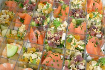 Rouleau de saumon, mangue et concombre présenté sur une petite assiette en bois.