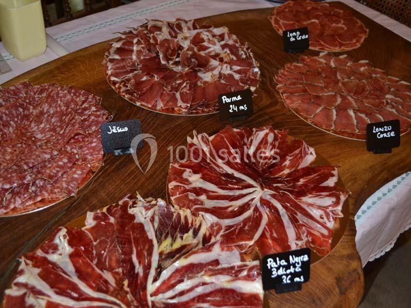 Assortiment de charcuteries variées disposées sur des plateaux en bois avec des étiquettes indiquant les noms des produits.