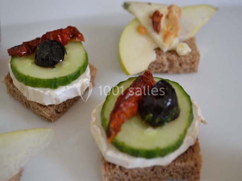 Canapés sur pain complet garnis de fromage, concombre, olive noire, tomate séchée et morceaux de pomme avec noix.