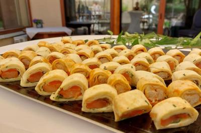 Rouleau de saumon, mangue et concombre présenté sur une petite assiette en bois.