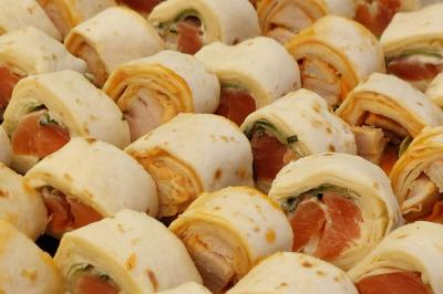 Rouleau de saumon, mangue et concombre présenté sur une petite assiette en bois.