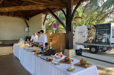 Décoration d'une tente événementielle avec tables ornées, barils en bois, fleurs et ballons dans un espace extérieur.