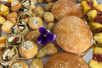 Décoration d'une tente événementielle avec tables ornées, barils en bois, fleurs et ballons dans un espace extérieur.