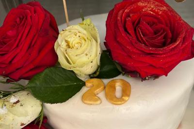 Décoration d'une tente événementielle avec tables ornées, barils en bois, fleurs et ballons dans un espace extérieur.