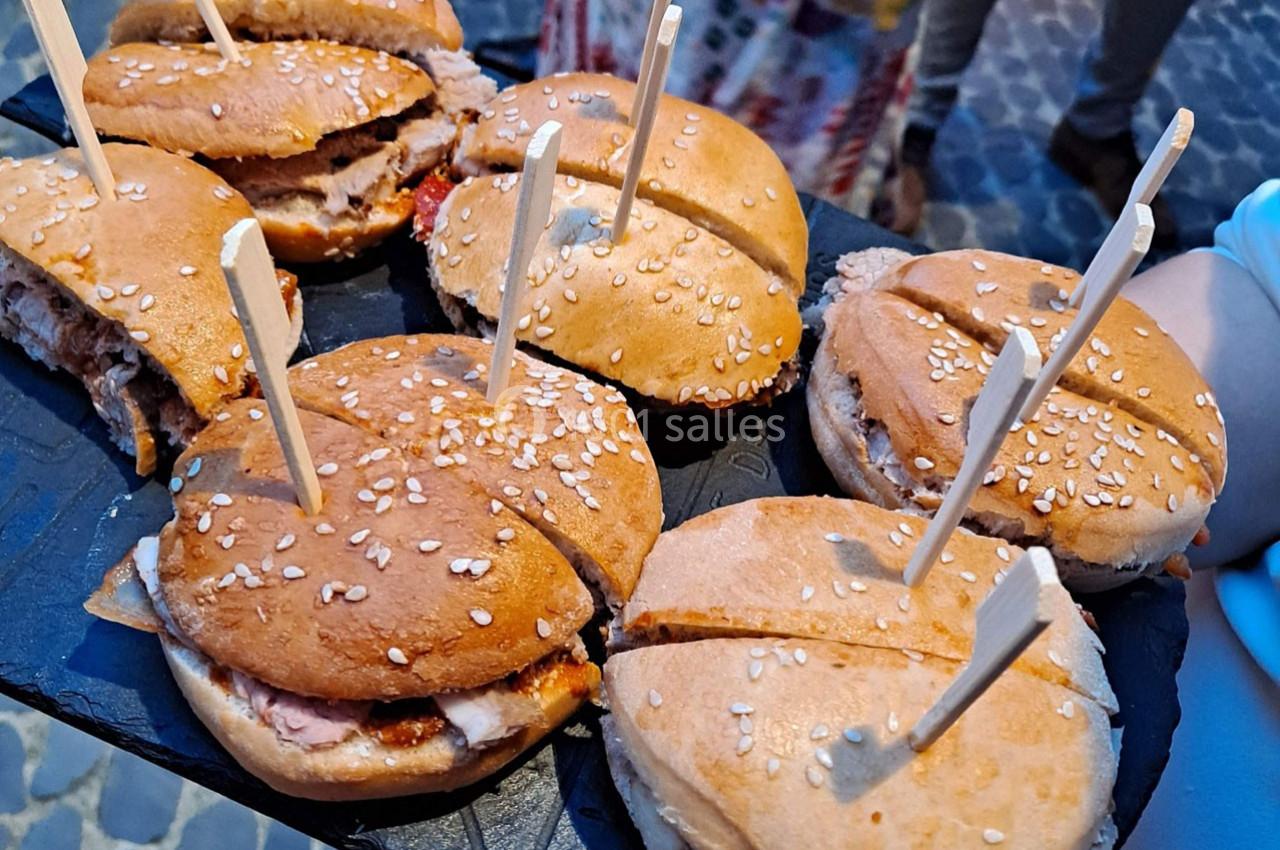 Plateau de mini-burgers au pain brioché et graines de sésame, chacun maintenu par un pic en bois.