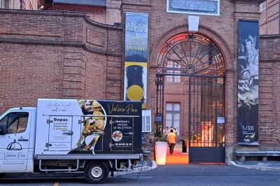Décoration d'une tente événementielle avec tables ornées, barils en bois, fleurs et ballons dans un espace extérieur.