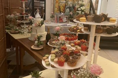 Décoration d'une tente événementielle avec tables ornées, barils en bois, fleurs et ballons dans un espace extérieur.