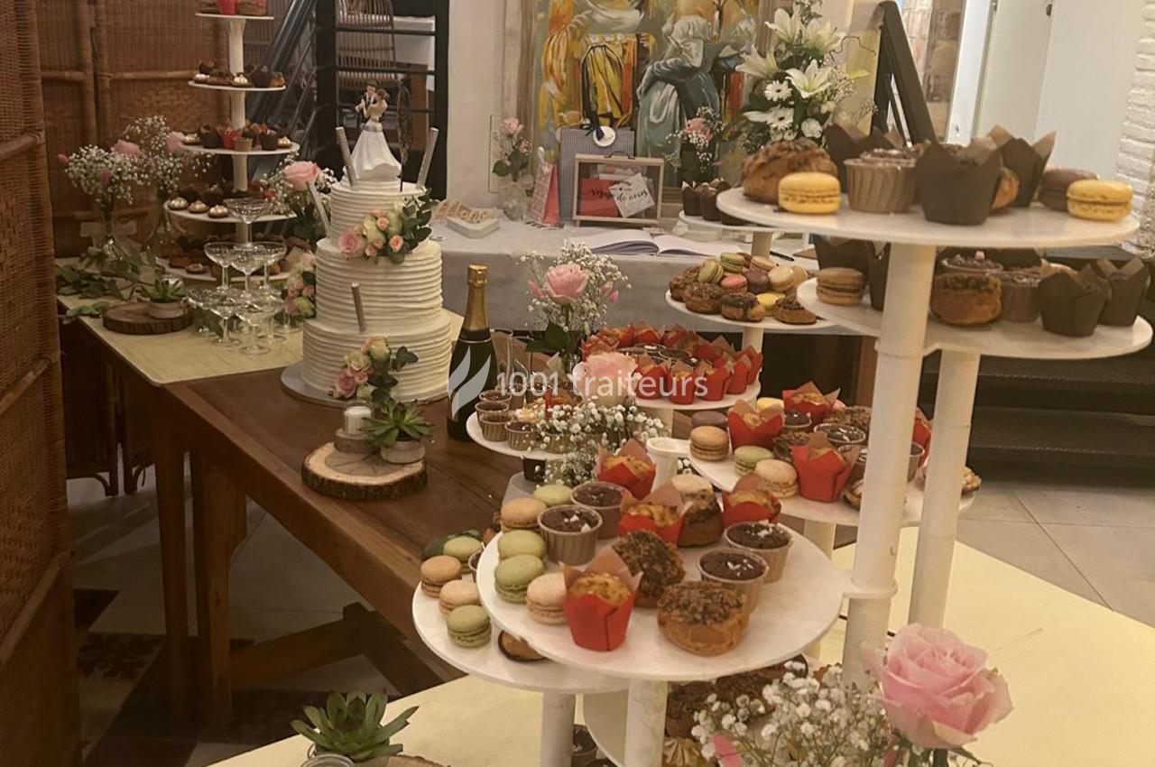 Table garnie de desserts variés, macarons, cupcakes et pièce montée, décorée de fleurs et éléments festifs.