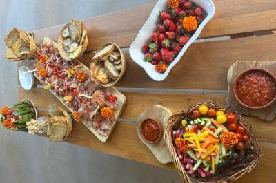 Décoration d'une tente événementielle avec tables ornées, barils en bois, fleurs et ballons dans un espace extérieur.