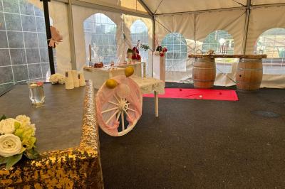 Décoration d'une tente événementielle avec tables ornées, barils en bois, fleurs et ballons dans un espace extérieur.