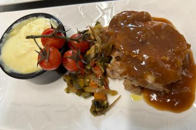 Décoration d'une tente événementielle avec tables ornées, barils en bois, fleurs et ballons dans un espace extérieur.