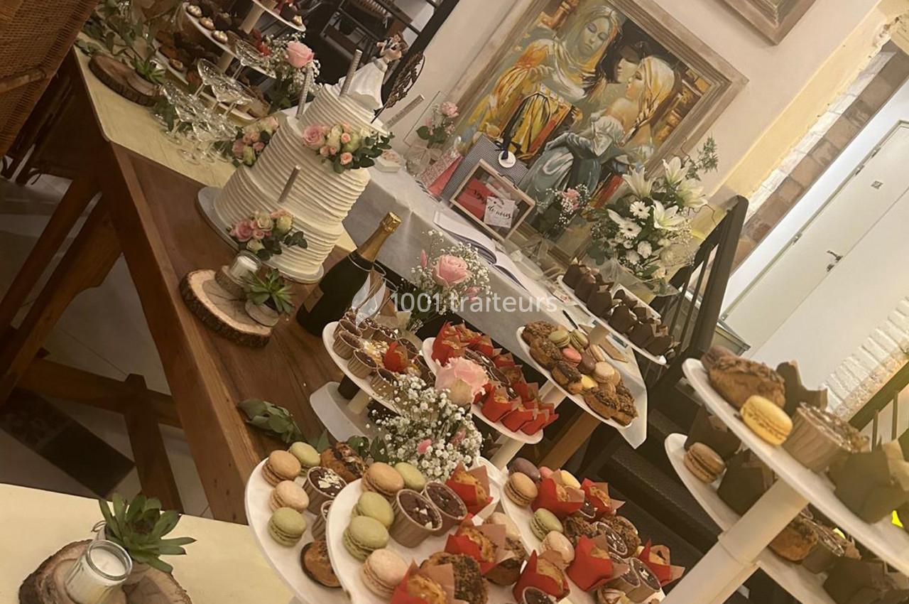 Table garnie de desserts variés, macarons, gâteaux et décorations florales dans un cadre intérieur chaleureux.