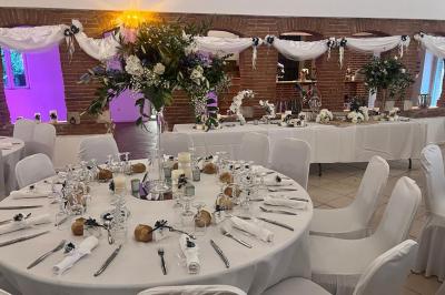 Décoration d'une tente événementielle avec tables ornées, barils en bois, fleurs et ballons dans un espace extérieur.