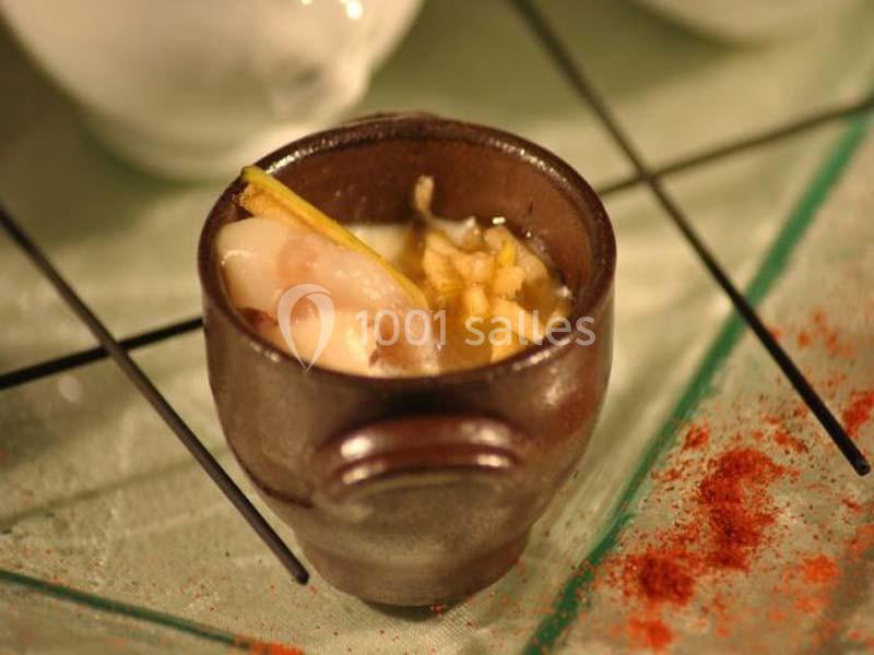 Bol en céramique contenant une préparation culinaire avec des morceaux de poisson, des légumes et une garniture.