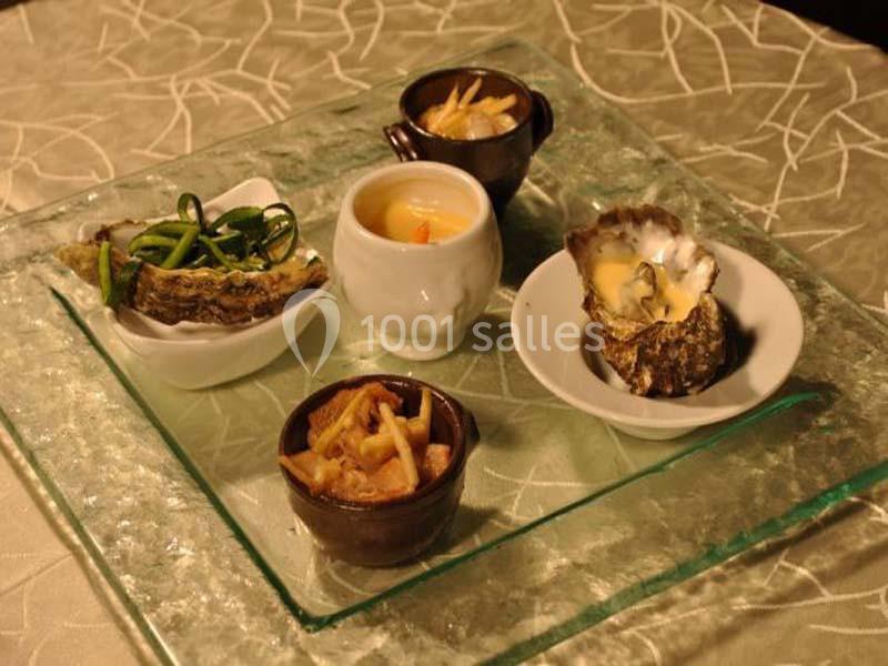 Assortiment de plats gastronomiques comprenant fruits de mer, légumes et une petite soupe, présenté sur une table élégante.