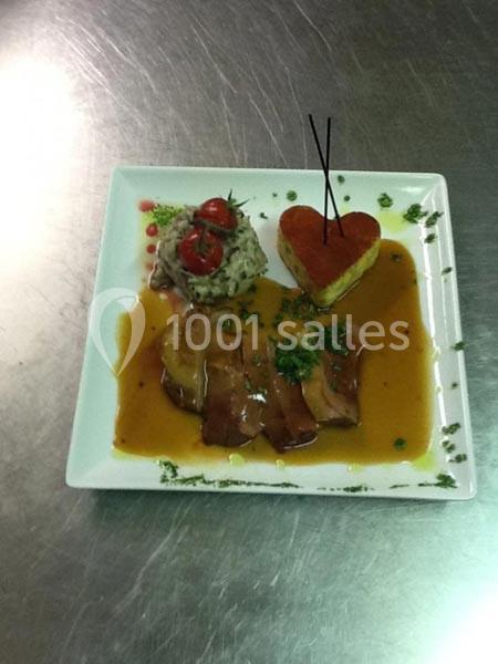 Assiette gastronomique avec viande en sauce, accompagnée de légumes, tomates cerises et garniture en forme de cœur.