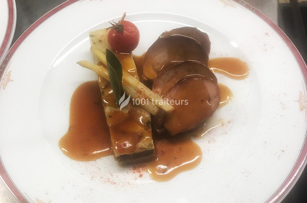 Assiette gastronomique avec viande nappée de sauce, accompagnée de légumes et d'un flan salé, décorée d'une tomate cerise.