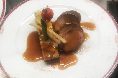 Assiette de poisson en sauce blanche, garnie de persil frais, légumes et décorée de traits de sauce verte.