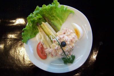 Pyramide de macarons colorés surmontée de figurines de mariés, présentée sur une table rouge en extérieur.