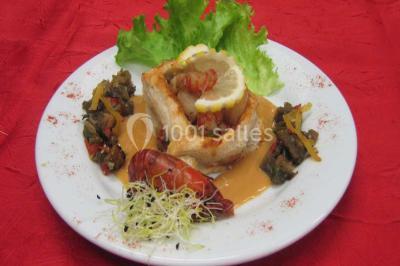 Pyramide de macarons colorés surmontée de figurines de mariés, présentée sur une table rouge en extérieur.