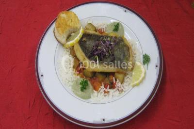 Pyramide de macarons colorés surmontée de figurines de mariés, présentée sur une table rouge en extérieur.