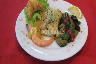 Pyramide de macarons colorés surmontée de figurines de mariés, présentée sur une table rouge en extérieur.