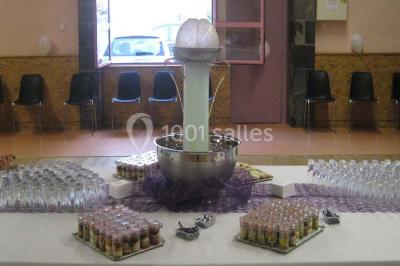 Pyramide de macarons colorés surmontée de figurines de mariés, présentée sur une table rouge en extérieur.