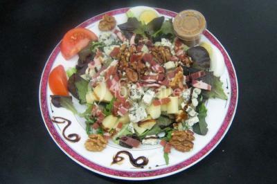 Pyramide de macarons colorés surmontée de figurines de mariés, présentée sur une table rouge en extérieur.