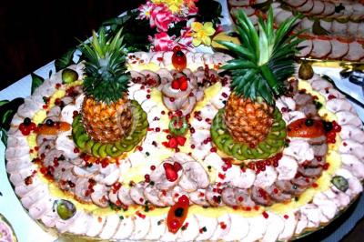 Pyramide de macarons colorés surmontée de figurines de mariés, présentée sur une table rouge en extérieur.