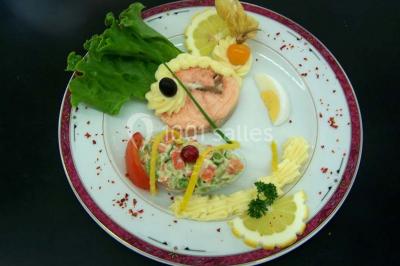 Pyramide de macarons colorés surmontée de figurines de mariés, présentée sur une table rouge en extérieur.