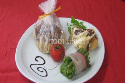 Pyramide de macarons colorés surmontée de figurines de mariés, présentée sur une table rouge en extérieur.