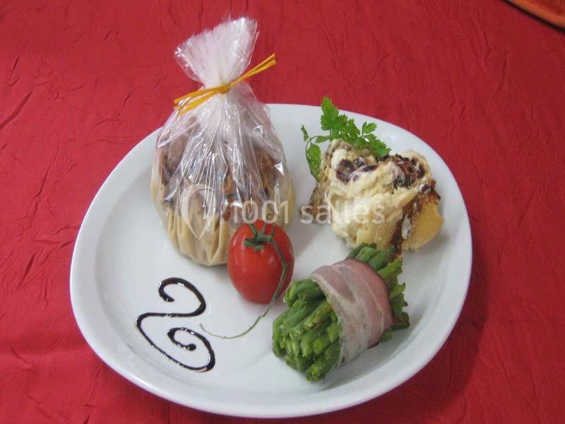 Assiette garnie d'un ballotin, d'un fagot d'haricots verts enroulés de lard, d'une tomate et d'une sauce décorative.