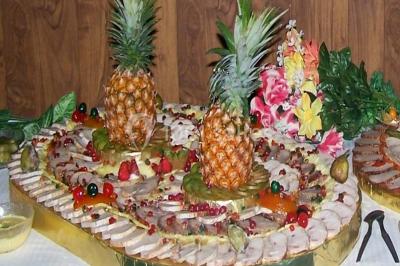 Pyramide de macarons colorés surmontée de figurines de mariés, présentée sur une table rouge en extérieur.