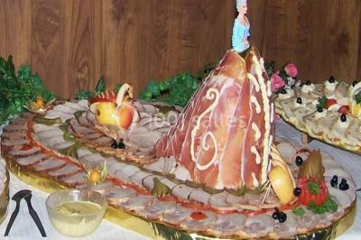 Pyramide de macarons colorés surmontée de figurines de mariés, présentée sur une table rouge en extérieur.