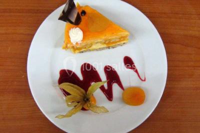 Pyramide de macarons colorés surmontée de figurines de mariés, présentée sur une table rouge en extérieur.