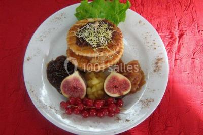 Pyramide de macarons colorés surmontée de figurines de mariés, présentée sur une table rouge en extérieur.