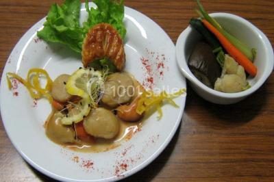 Pyramide de macarons colorés surmontée de figurines de mariés, présentée sur une table rouge en extérieur.