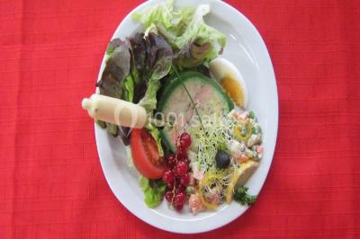 Pyramide de macarons colorés surmontée de figurines de mariés, présentée sur une table rouge en extérieur.