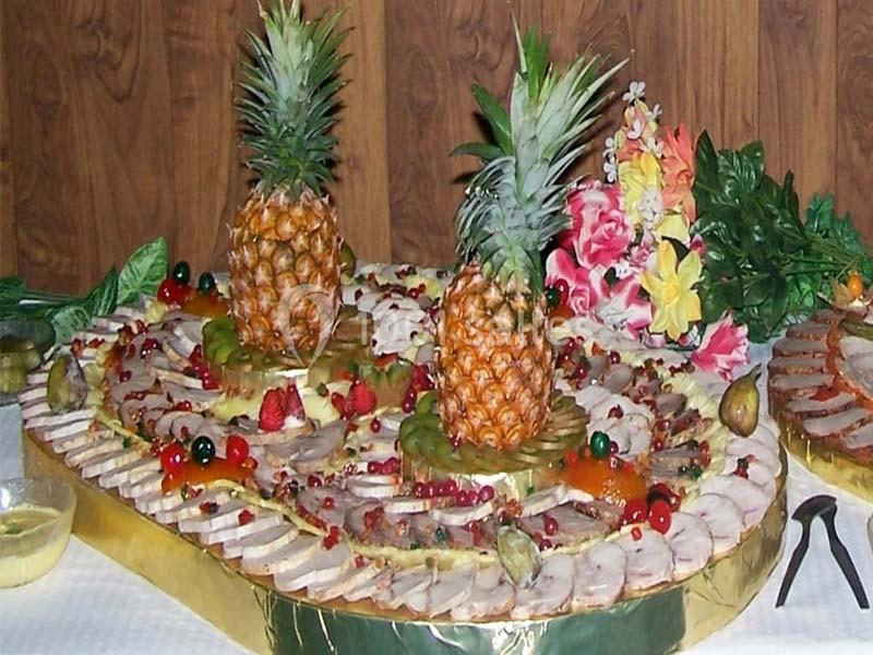 Plateau de charcuterie et fruits décoré avec des tranches d'ananas, des figues, des baies et des fleurs tropicales.